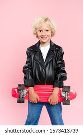 Smiling And Cute Kid Holding Penny Board Isolated On Pink