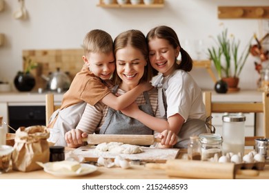 Smiling cute kids: son and daughter  embracing mother rolling dough at wooden table while preparing bakery in kitchen  - Powered by Shutterstock