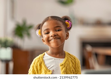 Smiling cute little african american girl and two pony tails looking at camera  Portrait happy female child at home  Smiling face black 4 year old girl looking at camera and afro puff hair 