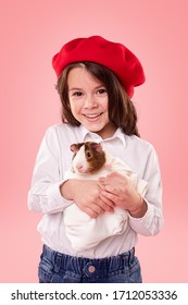 Smiling cute stylish kid girl with guinea pig against pink background