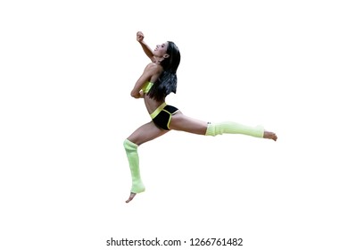 Smiling Dancer In Sportswear Jumping High Isolated On White. Brunette In Yellow And Black Clothes And Legwarmers In Long Jump. Aerial Choreographic Pose Of Attractive Female On White Background.