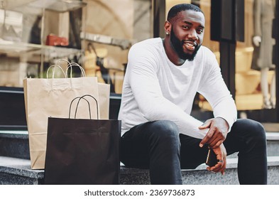 smiling dark skinned guy looking at camera enjoying recreation after buying purchases