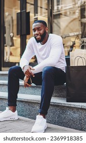 smiling dark skinned guy looking at camera enjoying recreation after buying purchases