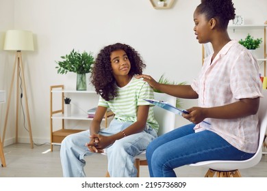 Smiling Dark-skinned Teenage Girl Attends Therapy Session With Young Female Child Psychologist. Caring African American Woman Social Worker Works With Girl To Solve Teenage Problems.