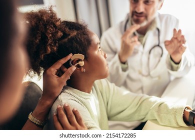 Smiling deaf african american girl with ear implant at doctor's office. - Shutterstock ID 2154172285