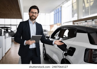 Smiling dealer showcasing electric car in modern vehicle dealership. Professional salesman using tablet making car sale presentation. Futuristic environment highlighting eco-friendly technology. - Powered by Shutterstock