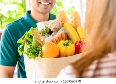 Smiling Delivery Man Giving Grocery Bag To Woman Customer At Home For Online Food Shopping Service Concept