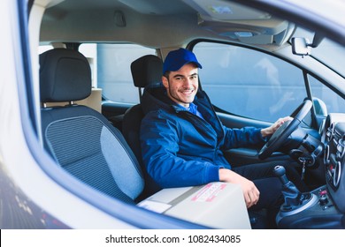 Smiling Delivery Man Sitting In The Car As A Driver