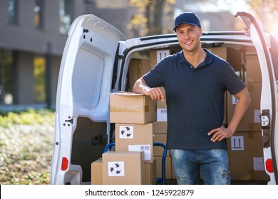 Smiling delivery man standing in front of his van