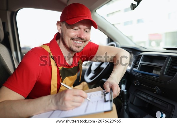 Smiling delivery service worker fill in\
necessary documents after\
shipping