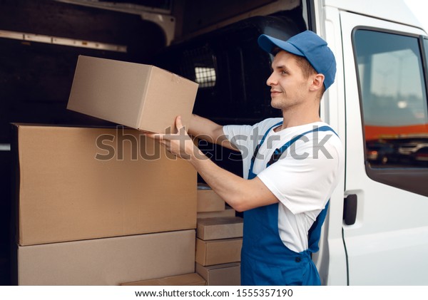 Smiling\
deliveryman with carton box at the\
car