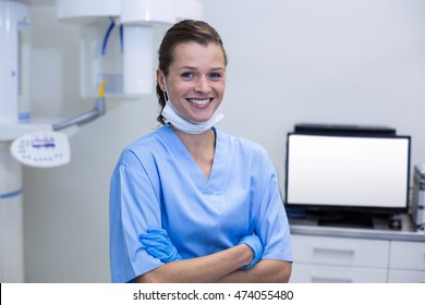 Smiling dental assistant standing with arms crossed in dental clinic