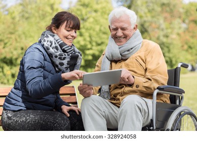 Smiling disabled man and caregiver with a tablet - Powered by Shutterstock