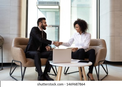 Smiling diverse business partners shaking hands at meeting, greeting, African American businesswoman and Caucasian businessman handshaking, making agreement, successful job interview or negotiations