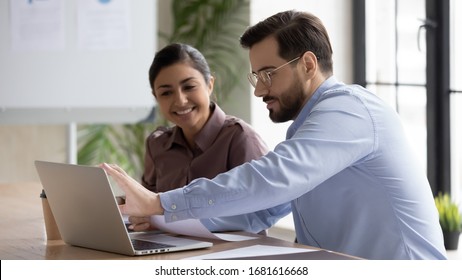 Smiling diverse businesspeople sit at desk work on laptop together discussing project or idea, happy multiracial colleagues cooperate using computer gadget, brainstorm at office meeting - Powered by Shutterstock