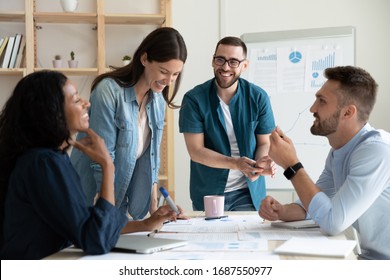 Smiling diverse colleagues gather in boardroom brainstorm discuss financial statistics together, happy multiracial coworkers have fun cooperating working together at office meeting, teamwork concept - Shutterstock ID 1687550977