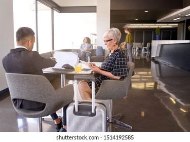 Smiling diverse colleagues sitting in modern airport lounge with baggage developping business ideas together - Powered by Shutterstock