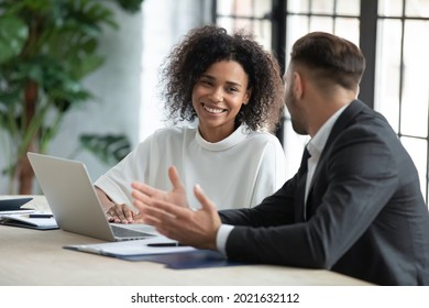 Smiling diverse employees colleagues have fun laugh cooperate brainstorm on computer at office team meeting. Happy multiethnic businesspeople work together on laptop discuss business ideas in group. - Shutterstock ID 2021632112