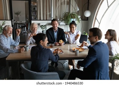 Smiling diverse employees sit in office have fun enjoy pizza on work lunch break together. Happy multiethnic colleagues coworkers laugh joke eating Italian fast food meal, drink coffee at workplace. - Powered by Shutterstock