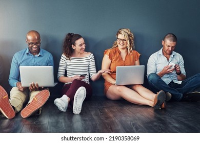 Smiling, Diverse Group Of Casual And Modern Business People With Their Digital Devices On Social Media Networking Apps. Happy, Connected Team Of Colleagues Sitting, Working On Laptop Pcs And Phones