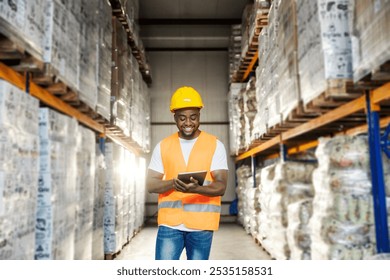 Smiling diverse industry worker standing at storage with tablet in hands and tracking shipment. - Powered by Shutterstock