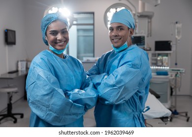 Smiling diverse male female surgeons with face masks and protective clothing in operating theatre. medicine, health and healthcare services during covid 19 coronavirus pandemic. - Powered by Shutterstock