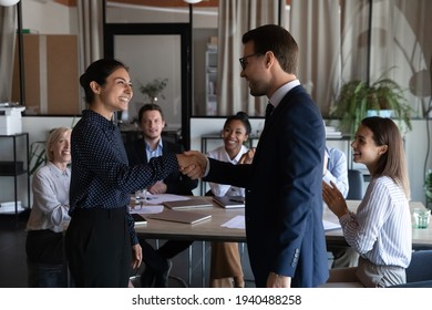 Smiling Diverse Multiracial Employees Handshake Close Deal Agreement At Meeting. Happy Multiethnic Businesspeople Shake Hand Get Acquainted Greet At Briefing, Congratulate Colleague With Promotion.