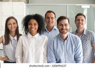 Smiling diverse office workers group, happy multiracial professional members employees looking at camera, motivated staff business people posing together, multi-ethnic workforce sales team portrait