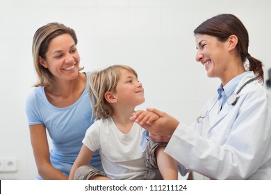 Smiling Doctor Auscultating The Forearm Of A Child In Examination Room, Healthcare Workers In The Coronavirus Covid19 Pandemic