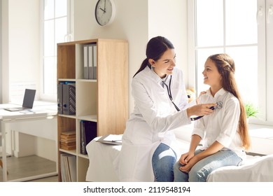 Smiling doctor checking child's lungs during medical checkup in modern sunny exam room at the clinic. Friendly female pediatrician using stethoscope to examine breathing and heartbeat of young patient