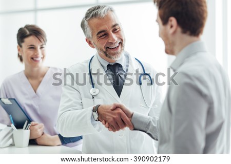 Smiling doctor at the clinic giving an handshake to his patient, healthcare and professionalism concept