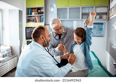 Smiling doctor examining child with stethoscope in medical office - Powered by Shutterstock