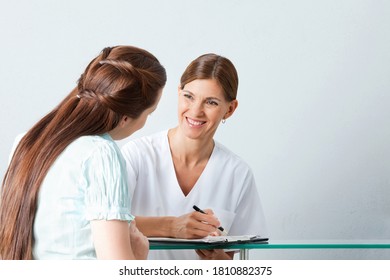 Smiling Doctor Fills Out Questionnaire With A Patient