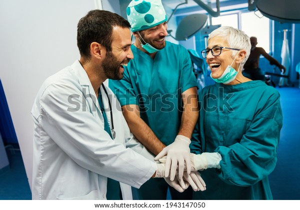 Smiling doctor giving high five\
after successful surgery. Healthcare, success, doctor\
concept
