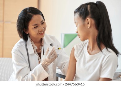 Smiling doctor injecting vaccine in arm of teenage girl - Powered by Shutterstock