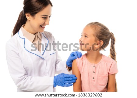 Smiling doctor in latex gloves looking at kid isolated on white