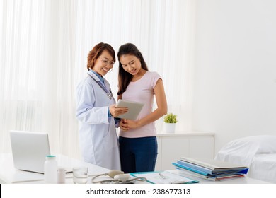 Smiling doctor and patient discussing medical test results using a digital tablet