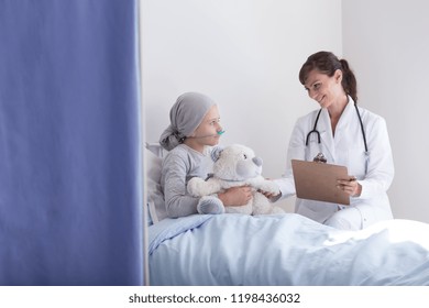 Smiling Doctor With Stethoscope Talking With Kid With Cancer Hugging Plush Toy