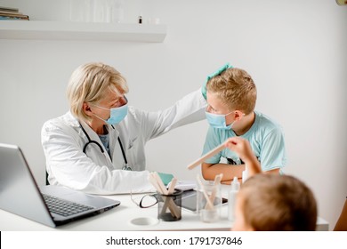 Smiling Doctor Talking With A Boy. They Are Wearing A Protective Face Mask. 