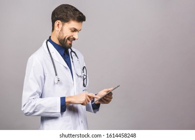 Smiling doctor using a tablet computer isolated on a grey background.