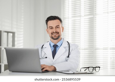 Smiling doctor working with laptop at table in clinic - Powered by Shutterstock