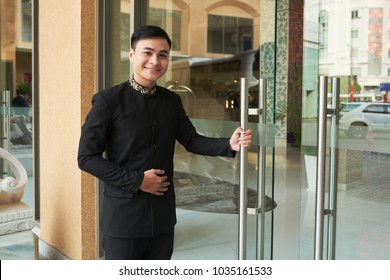 Smiling Doorman Standing At Hotel Entrance