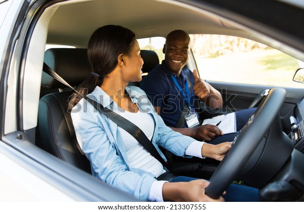 smiling driving instructor giving thumbs up to\
learner driver during\
test