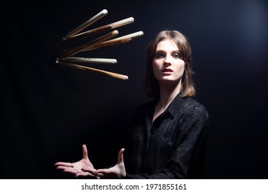 Smiling Drummer Woman With Drum Sticks Young Beautiful Musician Girl Tossing Up Effectively Drum Sticks. Dramatic Portrait On Black Background