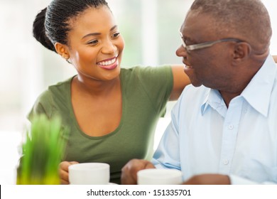 smiling elderly african american man enjoying coffee with his granddaughter at home - Powered by Shutterstock