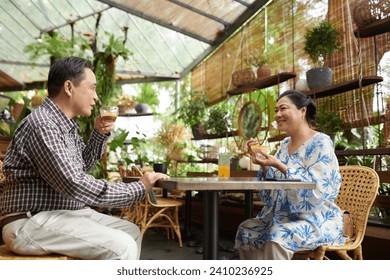 Smiling elderly couple having coffee and desserts in cafe - Powered by Shutterstock