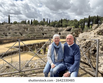 A smiling elderly couple posing for a memory photography during a sightseeing trip to an archaeological site, enjoying the culture and leisurely retirement lifestyle