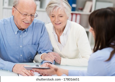 Smiling elderly couple receiving financial advice from a female broker who is showing them a calculator - Powered by Shutterstock