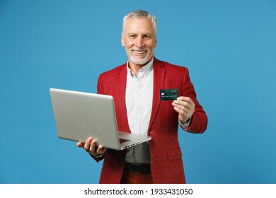 Smiling Elderly Gray-haired Mustache Bearded Business Man Wearing Red Jacket Suit Standing Working On Laptop Pc Computer Hold Credit Bank Card Isolated On Blue Color Wall Background Studio Portrait