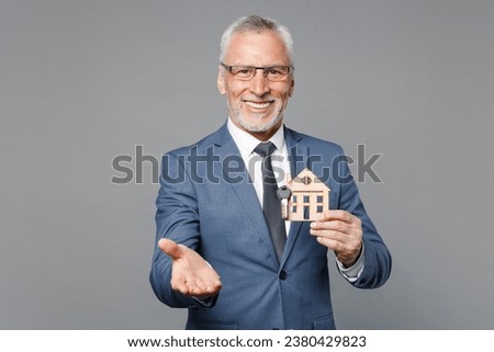 Smiling elderly gray-haired mustache bearded business man in blue suit shirt isolated on grey background. Achievement career wealth business concept. Hold house bunch of keys, pointing hand on camera